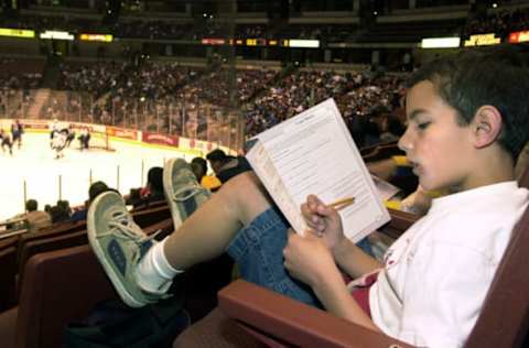 Sierra Vista elementary fourth grader, Ryan Saldana, 9, does the workbook activities while the Ducks play a scrimmage at the Pond in Anaheim. The Third annual First Flight Field trip, an educational experience that integrates the National Hockey League with learning. Each student receives an educational workbook to complete during the Mighty Ducks practice. The Workbook focuses on subjects such as world geography, mathematics, general history, teamwork, fitness, and nutrition. (Photo by Geraldine Wilkins/Los Angeles Times via Getty Images)