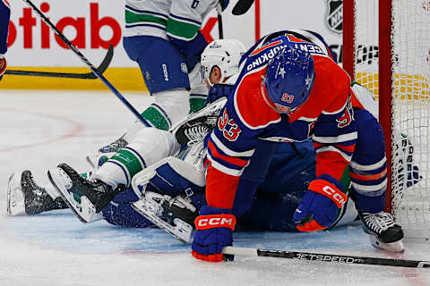 Oct 14, 2023; Edmonton, Alberta, CAN; Edmonton Oilers forward Ryan Nugent-Hopkins (93) and Vancouver Canucks defensemen Ian Cole (82) fall onto goaltender Casey DeSmith (29) during the first period at Rogers Place. Mandatory Credit: Perry Nelson-USA TODAY Sports