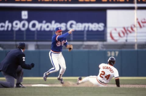 BALTIMORE, MD – CIRCA 1985: Toby Harrah #11 of the Texas Rangers gets his throw off to first base while avoiding the slide of Rick Dempsey #24 of the Baltimore Orioles during an Major League baseball game circa 1985 at Memorial Stadium in Baltimore, Maryland. Harrah played for the Washington Senators/Texas Rangers from 1969-78 and 1985-86. (Photo by Focus on Sport/Getty Images)