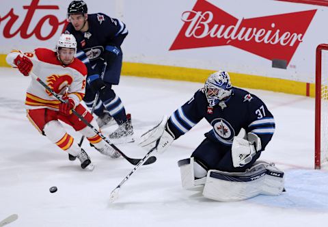 WINNIPEG, CANADA – APRIL 5: Connor Hellebuyck #37 of the Winnipeg Jets follows a rebound with Andrew Mangiapane #88 of the Calgary Flames and teammate Dylan DeMelo #2 in the third period during a game on April 5, 2023 at Canada Life Centre in Winnipeg, Manitoba, Canada. (Photo by Jason Halstead/Getty Images)