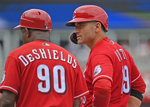 Jul 7, 2021; Kansas City, Missouri, USA; Cincinnati Reds designated hitter Joey Votto (19) talks with first base coach Delino DeShields (90) after hitting a single during the fourth inning against the Kansas City Royals at Kauffman Stadium. Mandatory Credit: Peter Aiken-USA TODAY Sports