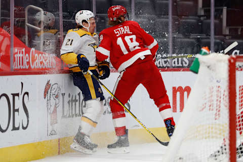 Feb 25, 2021; Detroit, Michigan, USA; Nashville Predators center Nick Cousins (21) gets checked against the boards by Detroit Red Wings defenseman Marc Staal (18)  . Mandatory Credit: Raj Mehta-USA TODAY Sports