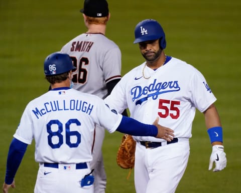 May 17, 2021; Los Angeles, California, USA; Los Angeles Dodgers first baseman Albert Pujols (55) is congratulated by first base coach Clayton McCullough after singling in a run against the Arizona Diamondbacks in the third inning at Dodger Stadium. Mandatory Credit: Robert Hanashiro-USA TODAY Sports