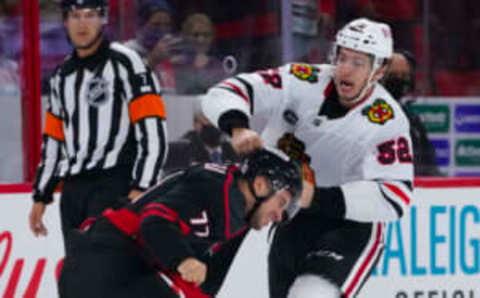 Oct 29, 2021; Raleigh, North Carolina, USA; Carolina Hurricanes defenseman Tony DeAngelo (77) fights Chicago Blackhawks center Reese Johnson (52) during the third period at PNC Arena. Mandatory Credit: James Guillory-USA TODAY Sports