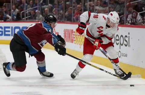 DENVER, COLORADO – DECEMBER 19: Ryan Graves #27 of the Colorado Avalanche fights for the puck against Ryan Dzingel #18 of the Carolina Hurricanes in the third period at the Pepsi Center on December 19, 2019 in Denver, Colorado. (Photo by Matthew Stockman/Getty Images)