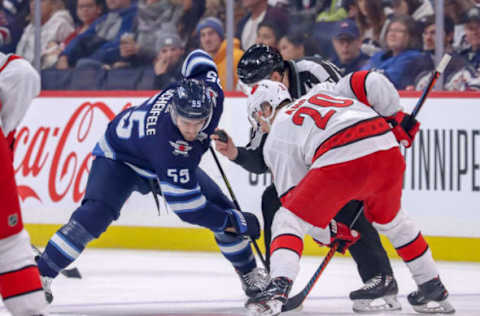 WINNIPEG, MB – DECEMBER 17: Mark Scheifele #55 of the Winnipeg Jets takes a first period face-off against Sebastian Aho #20 of the Carolina Hurricanes at the Bell MTS Place on December 17, 2019 in Winnipeg, Manitoba, Canada. (Photo by Darcy Finley/NHLI via Getty Images)