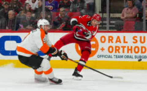 Mar 9, 2023; Raleigh, North Carolina, USA; Carolina Hurricanes center Jesperi Kotkaniemi (82) gets the shot away against Philadelphia Flyers defenseman Ivan Provorov (9) during the first period at PNC Arena. Mandatory Credit: James Guillory-USA TODAY Sports