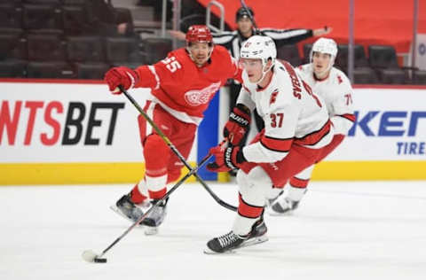 Mar 14, 2021; Detroit, Michigan, USA; Carolina Hurricanes right wing Andrei Svechnikov (37) skates the puck up ice as Detroit Red Wings defenseman Danny DeKeyser (65) defends during the first period at Little Caesars Arena. Mandatory Credit: Tim Fuller-USA TODAY Sports