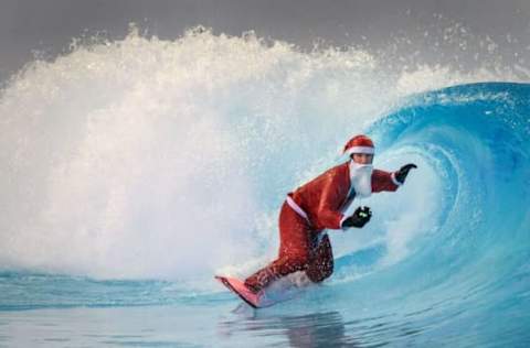 A surfer dressed as Santa Claus rides an artificial wave in a 0.6 degree (33 degrees Fahrenheit) water in the Alaia Bay surf wave pool surrounded by Swiss Alps, in Sion, on December 15, 2021. (Photo by Fabrice COFFRINI / AFP) (Photo by FABRICE COFFRINI/AFP via Getty Images)