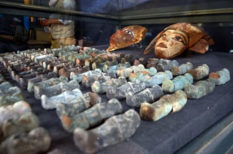 A picture taken on December 9, 2017 shows ancient Egyptian wooden funerary masks and small statuettes found in and retrieved from the newly discovered 'Kampp 150' tomb at Draa Abul Naga necropolis on the west Nile bank of the southern Egyptian city of Luxor, about 400 miles south of the capital Cairo.