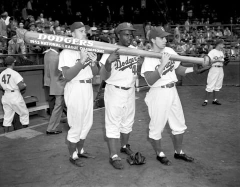 BROOKLYN, NY – OCTOBER 1952: (l to r) Outfielder Duke Snider #4, infielders Jackie Robinson #42 and Pee Wee Reese #1 of the Brooklyn Dodgers hold up an oversized bat which states the Dodgers are National League Champions for the 1952 season prior to a World Series game against the New York Yankees at Ebbets Field in Brooklyn, New York. (Olen Collection/Diamond Images/Getty Images)