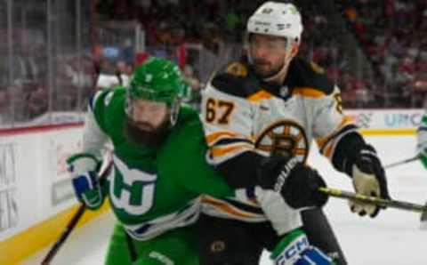 Mar 26, 2023; Raleigh, North Carolina, USA; Boston Bruins defenseman Jakub Zboril (67) and Carolina Hurricanes defenseman Brent Burns (8) battle during the first period at PNC Arena. Mandatory Credit: James Guillory-USA TODAY Sports