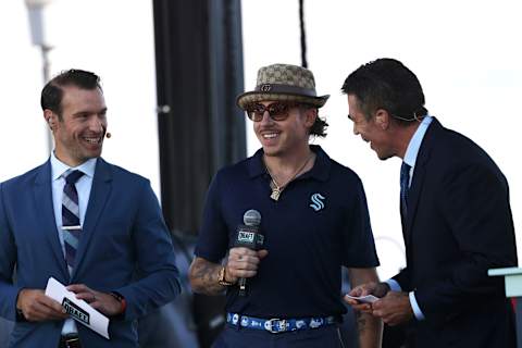 Grammy award winner, Macklemore, flanked by ESPN announcers Dominic Moore (L) and Chris Fowler (R) calls draft picks at the Seattle Kraken 2021 NHL Expansion Draft. (Photo by Karen Ducey/Getty Images)