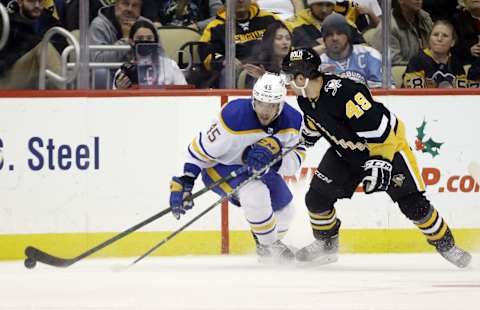 Dec 17, 2021; Pittsburgh, Pennsylvania, USA; Buffalo Sabres defenseman Casey Fitzgerald (45) moves the puck against Pittsburgh Penguins center Dominik Simon (49) during the third period at PPG Paints Arena. The Penguins won 3-2 in overtime. Mandatory Credit: Charles LeClaire-USA TODAY Sports