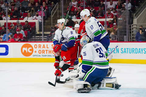 Jan 15, 2022; Raleigh, North Carolina, USA; Vancouver Canucks goaltender Thatcher Demko (35) defenseman Tyler Myers (57) and left wing Juho Lammikko (91) watch the shot against Carolina Hurricanes left wing Jordan Martinook (48) during the third period at PNC Arena. Mandatory Credit: James Guillory-USA TODAY Sports