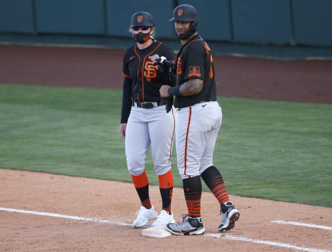 First base coach Alyssa Nakken #92 of the SF Giants bumps fists with Ricardo Genoves #91 after he walks during the sixth inning of the MLB spring training baseball game against the Los Angeles Angels at Tempe Diablo Stadium on March 11, 2021 in Tempe, Arizona. (Photo by Ralph Freso/Getty Images)