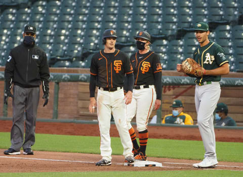 SF Giants center fielder Mike Yastrzemski (5) on first base with first base coach Alyssa Nakken (92) and Oakland Athletics first baseman Matt Olson (28) during the third inning at Oracle Park. (Kelley L Cox-USA TODAY Sports)