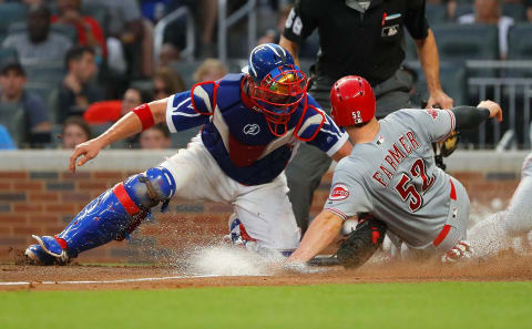 ATLANTA, GEORGIA – AUGUST 02: Kyle Farmer #52 of the Cincinnati Reds slides safely across home plate past a tag by Tyler Flowers #25 of the Atlanta Braves on a sacrifice fly by Joey Votto. (Photo by Kevin C. Cox/Getty Images)