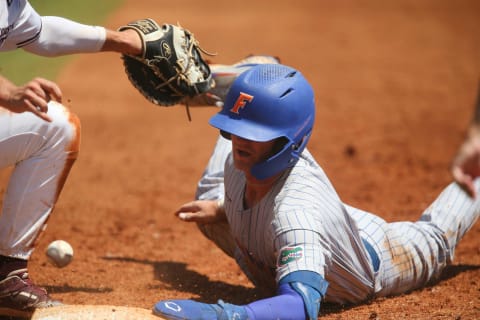 Florida base runner Jud Fabian (4) dives back into first after a snap throw. [Staff Photo/Gary Cosby Jr.]Sec Tournament Florida Vs Mississippi State