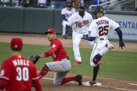 Jun 21, 2021; Minneapolis, Minnesota, USA; Minnesota Twins center fielder Byron Buxton (25) reaches first base before Cincinnati Reds first baseman Joey Votto (19) can catch the ball for a single. Mandatory Credit: Jesse Johnson-USA TODAY Sports