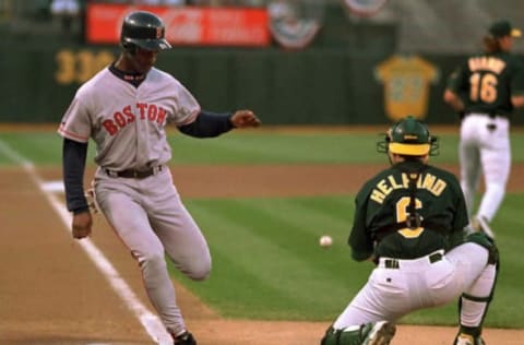 OAKLAND, : Boston Red Sox Willie McGee (L) scores at home while beating the tag from Oakland Athletics catcher Eric Helfand during the first inning 24 August in Oakland, California. McGee scored off a RBI double from teammate John Valentin as the Red Sox defeated the Athletics, 13-6. AFP PHOTOS (Photo credit should read JOHN G. MABANGLO/AFP via Getty Images)