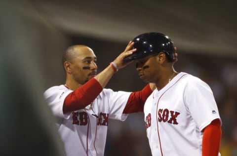 BOSTON, MASSACHUSETTS - JULY 17: Mookie Betts #50 of the Boston Red Sox removes Rafael Devers #11 of the Boston Red Sox helmet after he hits a solo home run in the bottom of the third inning of the game against the Toronto Blue Jays at Fenway Park on July 17, 2019 in Boston, Massachusetts. (Photo by Omar Rawlings/Getty Images)