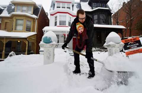 Mar 14, 2017; York, NY, USA; Tyler Snelbaker wears his daughter, 13-month-old Charlotte Snelbaker, as he shovels out his Lincoln Street home during Winter Storm Stella in York, New York. Mandatory Credit: Kate Penn/York Daily Record via USA TODAY NETWORK