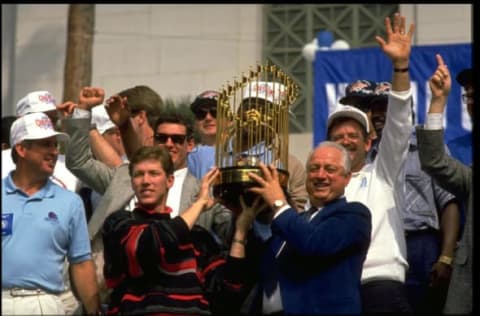 OCT 1988: TOMMY LASORDA, MANAGER OF THE LOS ANGELES DODGERS, AND OREL HERSHISER, PITCHER FOR THE DODGERS, HOIST THE MAJOR LEAGUE BASEBALL WORLD CHAMPIONSHIP TROPHY DURING THEIR 1988 CHAMPIONSHIP CELEBRATION AS OTHER MEMBERS OF THE TEAM WATCH FROM BEHIND.