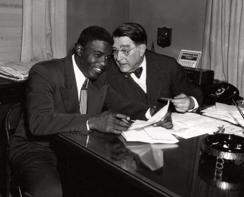 BROOKLYN – 1949. Jackie Robinson, left, and Branch Rickey share a joke during a contract signing session in the front offices of the Brooklyn Dodgers at Ebbets Field in Brooklyn in 1949. (Photo by Mark Rucker/Transcendental Graphics, Getty Images)