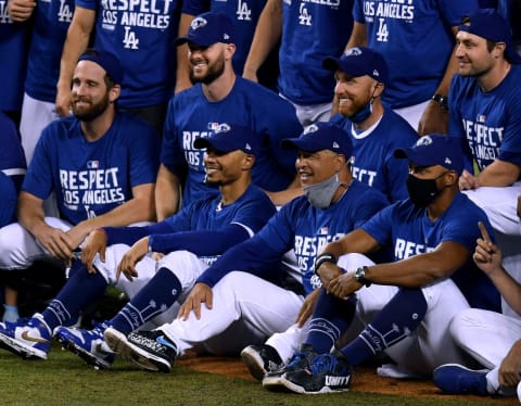 LOS ANGELES, CALIFORNIA – SEPTEMBER 22: Manager Dave Roberts #30 and Mookie Betts #50 of the Los Angeles Dodgers sit in the center of a team picture, after a 7-2 win over the Oakland Athletics, to win the National League West Division at Dodger Stadium on September 22, 2020 in Los Angeles, California. (Photo by Harry How/Getty Images)