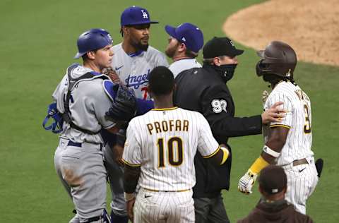 SAN DIEGO, CALIFORNIA - APRIL 16: Will Smith #16 and Max Muncy #13 hold back Dennis Santana #77 of the Los Angeles Dodgers as he challenged Jorge Mateo #3 after hitting him with a pitch as Jurickson Profar #10 of the San Diego Padres looks on while umpire Mark Ripperger #90 intervenes during the tenth inning of a game at PETCO Park on April 16, 2021 in San Diego, California. (Photo by Sean M. Haffey/Getty Images)