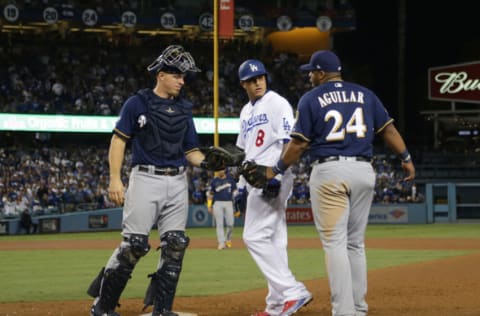 LOS ANGELES, CA - OCTOBER 16: Manny Machado #8 of the Los Angeles Dodgers and Jesus Aguilar #24 of the Milwaukee Brewers exchange words after Machado's foot hit Aguilar's on his way to being thrown out at first base as catcher Erik Kratz #15 of the Milwaukee Brewers looks on during the tenth inning of Game Four of the National League Championship Series at Dodger Stadium on October 16, 2018 in Los Angeles, California. (Photo by Jeff Gross/Getty Images)