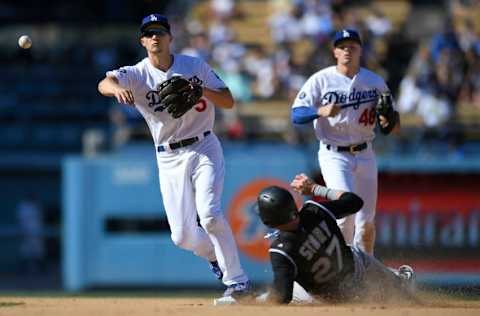 LOS ANGELES, CA - SEPTEMBER 22: Corey Seager #5 of the Los Angeles Dodgers throws to first from second as he catches Trevor Story #27 of the Colorado Rockies in a double play and Gavin Lux #48 looks on (Photo by John McCoy/Getty Images)