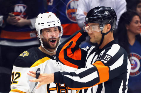 Craig Smith #12 of the Boston Bruins argues a second-period penalty with referee Jean Hebert #15 during the game against the New York Islanders. (Photo by Bruce Bennett/Getty Images)