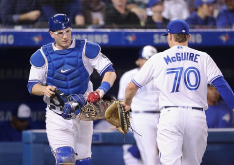 TORONTO, ON – SEPTEMBER 25: Danny Jansen #9 of the Toronto Blue Jays taps gloves with Reese McGuire #70 who helped him warm up the pitcher before the start of the next inning during MLB game action against the Houston Astros at Rogers Centre on September 25, 2018 in Toronto, Canada. (Photo by Tom Szczerbowski/Getty Images)