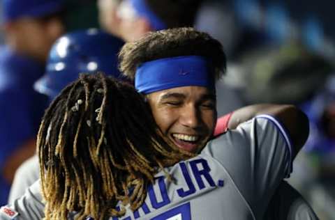 KANSAS CITY, MISSOURI – JULY 30: Vladimir Guerrero Jr. #27 of the Toronto Blue Jays is congratulated by Lourdes Gurriel Jr. #13 in the dugout after hitting a grand slam home run during the 9th inning of the game against the Kansas City Royals at Kauffman Stadium on July 30, 2019 in Kansas City, Missouri. (Photo by Jamie Squire/Getty Images)