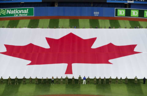 TORONTO, ON – APRIL 08: A large Canadian flag is unfurled on the field as the Canadian national anthem is sung ahead of the MLB game between the Toronto Blue Jays and the Texas Rangers on Opening Day at Rogers Centre on April 8, 2022 in Toronto, Canada. (Photo by Cole Burston/Getty Images)