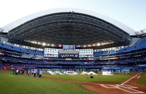 TORONTO, ON – JULY 30: The Toronto Blue Jays line up behind a ‘Home’ sign to commemorate their first home game in Toronto this season prior to a MLB game against the Kansas City Royals at Rogers Centre on July 30, 2021 in Toronto, Canada. (Photo by Vaughn Ridley/Getty Images)