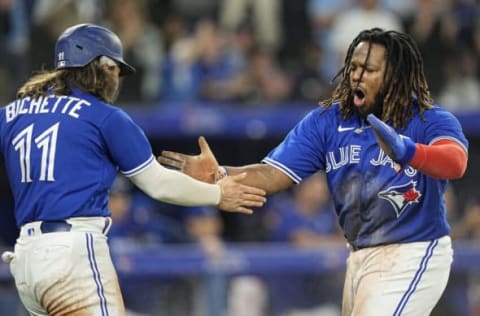 Sep 26, 2022; Toronto, Ontario, CAN; Toronto Blue Jays shortstop Bo Bichette (11) and first baseman Vladimir Guerrero Jr. (27) celebrates scoring on a double hit by right fielder Teoscar Hernandez (not pictured) against the New York Yankees during the fourth inning at Rogers Centre. Mandatory Credit: John E. Sokolowski-USA TODAY Sports