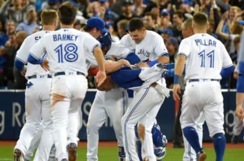 May 10, 2017; Toronto, Ontario, CAN; Toronto Blue Jays shortstop Ryan Goins (center) has his jersey ripped off by jubilant teammates after driving in the winning run in the ninth inning for an 8-7 victory over the Cleveland Indians at Rogers Centre. Mandatory Credit: Dan Hamilton-USA TODAY Sports