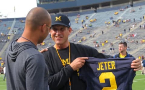 ANN ARBOR, MI – SEPTEMBER 26: Head coach Jim Harbaugh (R) of the Michigan Wolverines presents baseball great Derek Jeter (L) of the New York Yankees with a jersey prior to the game against the Brigham Young Cougars at Michigan Stadium on September 26, 2015 in Ann Arbor, Michigan. The Wolverines defeated the Cougars 31-0. (Photo by Doug Pensinger/Getty Images)