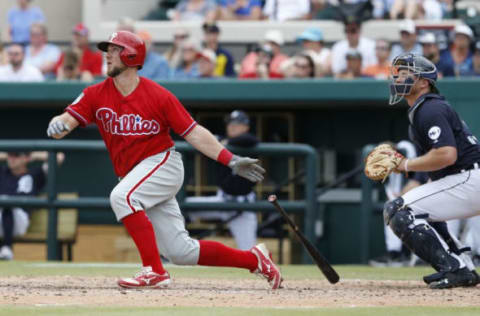 Mar 7, 2017; Lakeland, FL, USA; Philadelphia Phillies catcher Bryan Holaday (left) hits a two run homer as Detroit Tigers catcher John Hicks (right) looks on during the seventh inning of an MLB spring training baseball game at Joker Marchant Stadium. The Phillies won 11-6. Mandatory Credit: Reinhold Matay-USA TODAY Sports