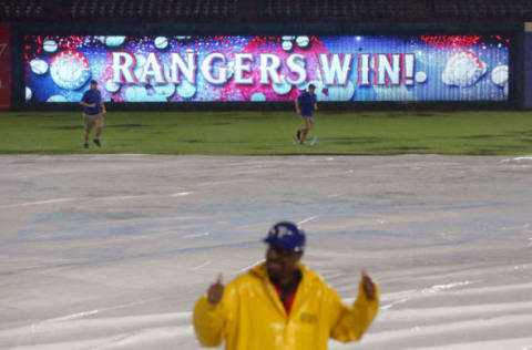 ARLINGTON, TX – SEPTEMBER 21: The grounds crew returns to the field as a security guard pumps his fists as the Rangers are declared the winner during a rain delay against the Seattle Mariners at Globe Life Park in Arlington on September 21, 2018 in Arlington, Texas. (Photo by Richard Rodriguez/Getty Images)