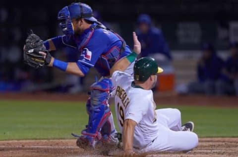 OAKLAND, CA – APRIL 22: Josh Phegley #19 of the Oakland Athletics scores on a sacrifice fly sliding in ahead of the throw to Jeff Mathis #2 of the Texas Rangers in the bottom of the third inning of a Major League Baseball game at Oakland-Alameda County Coliseum on April 22, 2019 in Oakland, California. (Photo by Thearon W. Henderson/Getty Images)