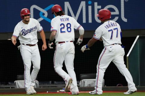 Oct 2, 2021; Arlington, Texas, USA; Texas Rangers catcher Jonah Heim (28) celebrates his three-run home run with designated hitter Nathaniel Lowe (left) and first baseman Andy Ibanez (77) during the fourth inning against the Cleveland Indians at Globe Life Field. Mandatory Credit: Jim Cowsert-USA TODAY Sports