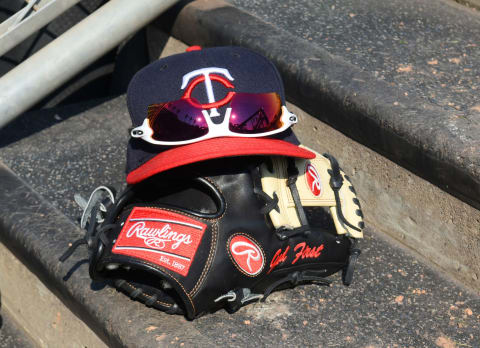 A detailed view of a Minnesota Twins baseball hat and a Rawlings glove sitting on the dugout steps. (Photo by Mark Cunningham/MLB Photos via Getty Images)