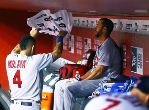 Apr 27, 2016; Phoenix, AZ, USA; St. Louis Cardinals catcher Yadier Molina (left) uses a towel to wave air on pitcher Adam Wainwright in the dugout after hitting three run triple in the sixth inning against the Arizona Diamondbacks at Chase Field. Mandatory Credit: Mark J. Rebilas-USA TODAY Sports