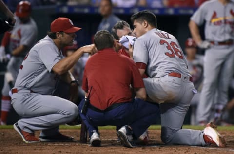 KANSAS CITY, MO - JUNE 27: Aledmys Diaz #36 of the St. Louis Cardinals is attended to by team trainers and manager Mike Matheny #22 after fouling a ball off the plate that struck him in the face in the ninth inning at Kauffman Stadium on June 27, 2016 in Kansas City, Missouri. (Photo by Ed Zurga/Getty Images)