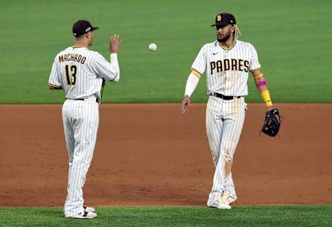 ARLINGTON, TEXAS – OCTOBER 08: Fernando Tatis Jr. #23 of the San Diego Padres tosses the ball to Manny Machado #13 during the ninth inning against the Los Angeles Dodgers in Game Three of the National League Division Series at Globe Life Field on October 08, 2020 in Arlington, Texas. (Photo by Tom Pennington/Getty Images)