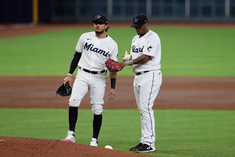 Oct 8, 2020; Houston, Texas, USA; Miami Marlins shortstop Miguel Rojas (left) looks on as starting pitcher Sixto Sanchez (right) applies rosin to his arm during the third inning of game three of the 2020 NLDS against the Atlanta Braves at Minute Maid Park. Mandatory Credit: Thomas Shea-USA TODAY Sports